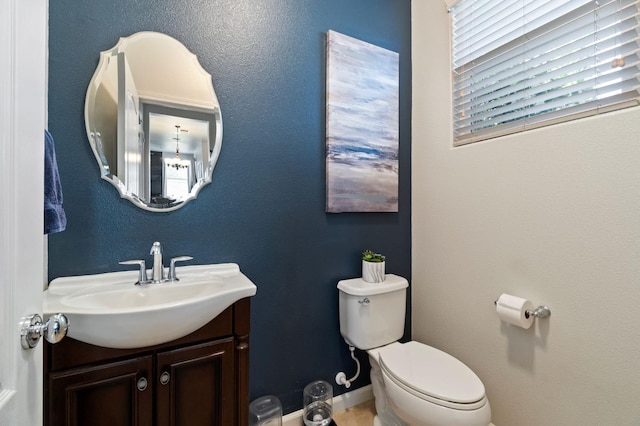 bathroom featuring toilet, vanity, and baseboards