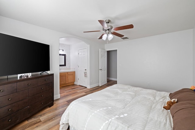 6675 E Montecito Ave, Fresno, CA 93727 - bedroom featuring light wood finished floors, visible vents, arched walkways, ensuite bath, and baseboards