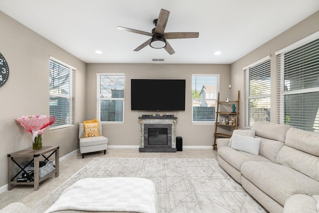 living room with a glass covered fireplace, baseboards, a ceiling fan, and visible vents