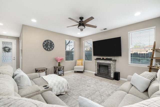 living area with a glass covered fireplace, a ceiling fan, baseboards, recessed lighting, and visible vents