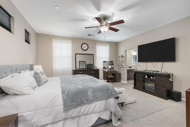 carpeted bedroom featuring a ceiling fan, visible vents, baseboards, connected bathroom, and a glass covered fireplace