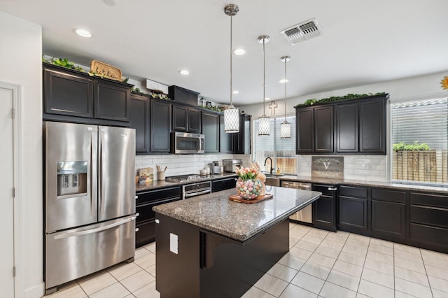 3821 Leigh Ln, Clovis, CA 93619 - kitchen featuring dark stone counters, light tile patterned flooring, appliances with stainless steel finishes, visible vents, and a kitchen island