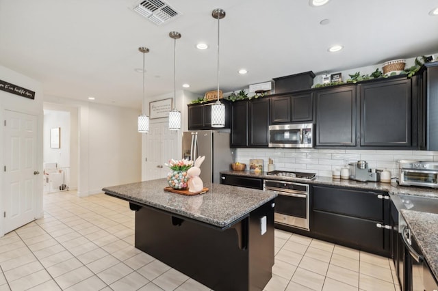 3821 Leigh Ln, Clovis, CA 93619 - kitchen with tasteful backsplash, a breakfast bar, stainless steel appliances, visible vents, and a kitchen island