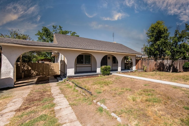 ranch-style house featuring fence, a porch, a front yard, and stucco siding