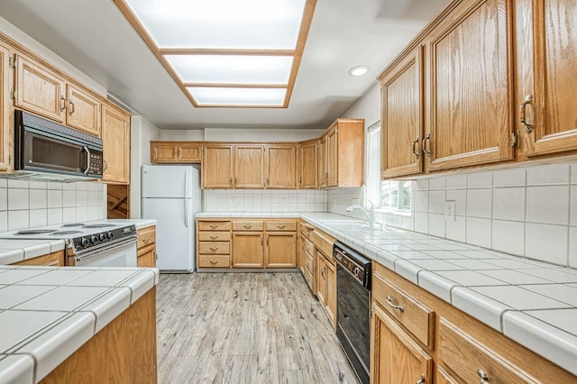 42153 Hemlock Ln, Shaver Lake, CA 93664 - kitchen featuring black appliances, a sink, decorative backsplash, light wood-style flooring, and tile countertops