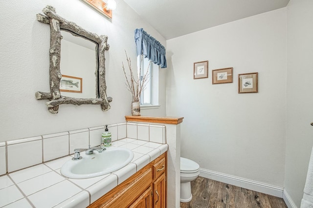 42153 Hemlock Ln, Shaver Lake, CA 93664 - half bathroom featuring toilet, wood finished floors, vanity, baseboards, and backsplash