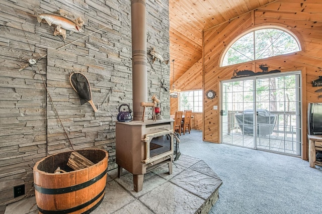 42153 Hemlock Ln, Shaver Lake, CA 93664 - living area with a wood stove, high vaulted ceiling, wooden walls, carpet flooring, and wooden ceiling