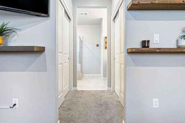 hallway featuring carpet floors, visible vents, and baseboards