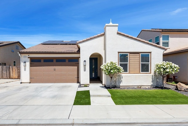 mediterranean / spanish-style house featuring stucco siding, a tile roof, roof mounted solar panels, driveway, and an attached garage
