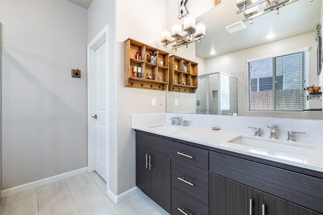 full bathroom featuring a sink, a stall shower, double vanity, baseboards, and a notable chandelier