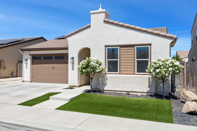 mediterranean / spanish home featuring an attached garage, stucco siding, fence, and concrete driveway