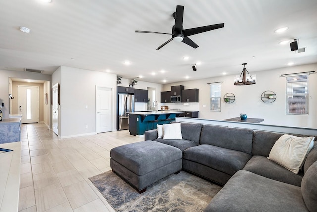 living room featuring ceiling fan with notable chandelier, baseboards, visible vents, and recessed lighting