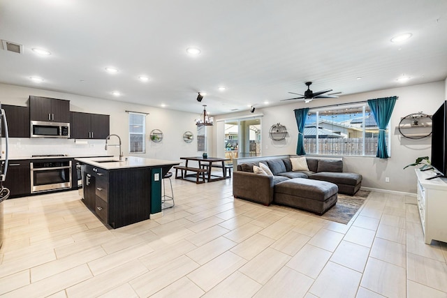 kitchen with a sink, open floor plan, visible vents, light countertops, and appliances with stainless steel finishes