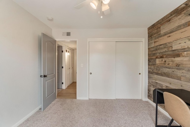 unfurnished office with ceiling fan, visible vents, carpet flooring, and wooden walls