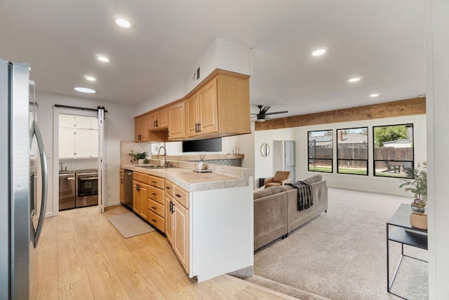 kitchen with stainless steel appliances, light countertops, a ceiling fan, a sink, and open floor plan