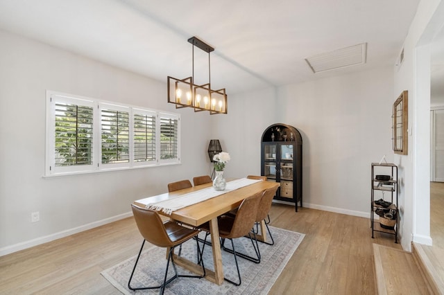 dining space featuring light wood-type flooring, visible vents, and baseboards