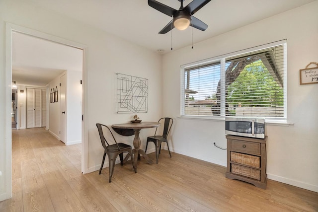 living area featuring light wood-style floors, baseboards, and ceiling fan