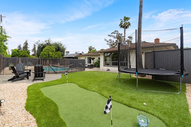 view of yard featuring a fenced backyard, a patio area, a fenced in pool, and a trampoline