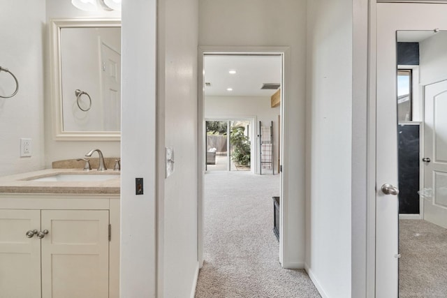 hall with baseboards, carpet flooring, and a sink