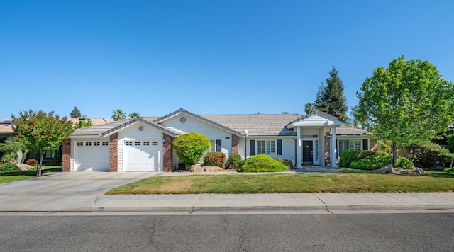 ranch-style house with a tile roof, a front lawn, driveway, brick siding, and an attached garage
