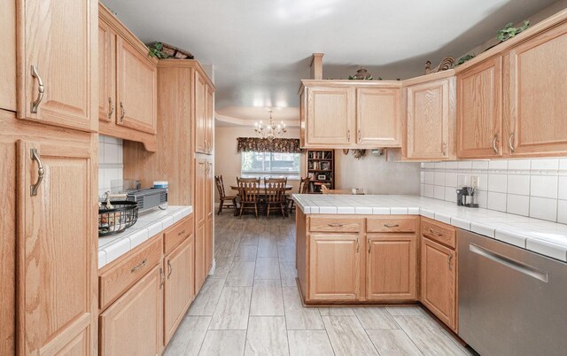 kitchen featuring light brown cabinetry, an inviting chandelier, dishwasher, tile countertops, and decorative backsplash