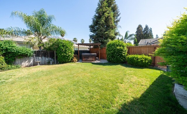 view of yard featuring a hot tub and a fenced backyard