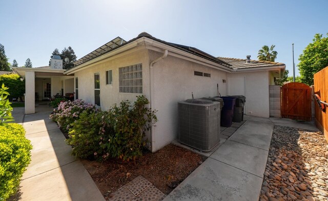 view of home's exterior featuring central air condition unit, a gate, a patio area, and stucco siding