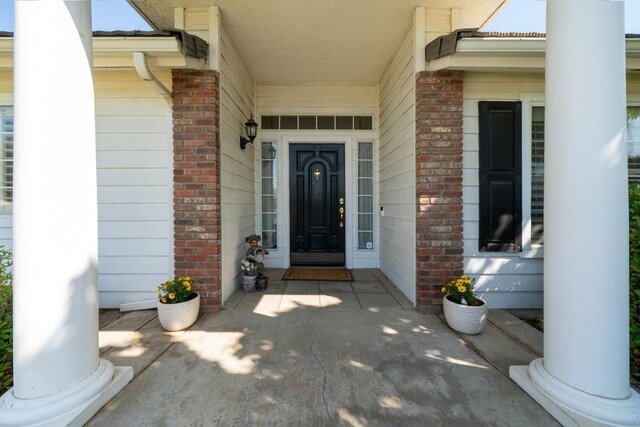 view of exterior entry featuring covered porch and brick siding