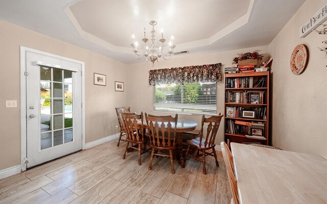 dining area with a raised ceiling, a wealth of natural light, and an inviting chandelier