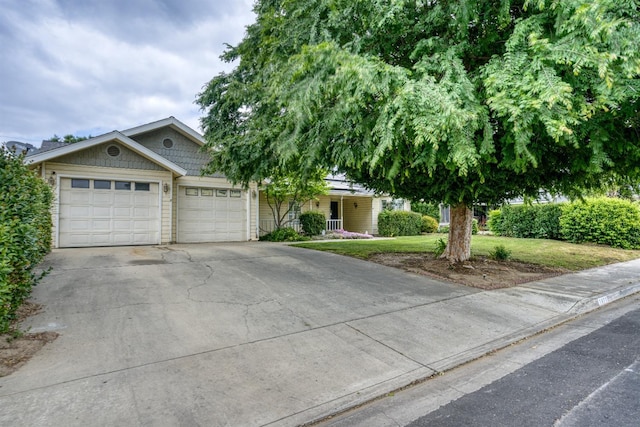 view of front of house featuring covered porch, an attached garage, a front yard, and concrete driveway