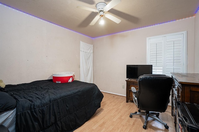 bedroom with light wood-style floors, a ceiling fan, and baseboards