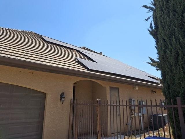 exterior space featuring fence, arched walkways, central AC unit, and stucco siding