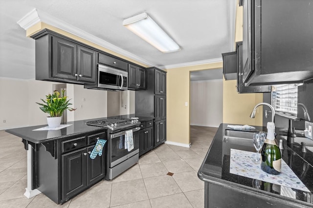 kitchen with light tile patterned floors, stainless steel appliances, dark cabinetry, baseboards, and ornamental molding