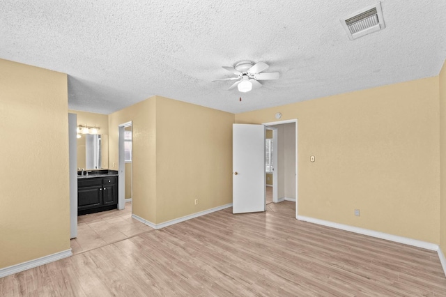 unfurnished bedroom featuring light wood finished floors, baseboards, visible vents, and connected bathroom