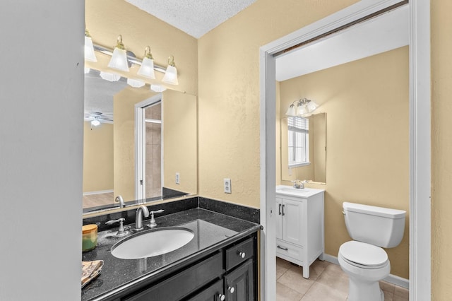 bathroom with two vanities, tile patterned floors, a sink, and toilet