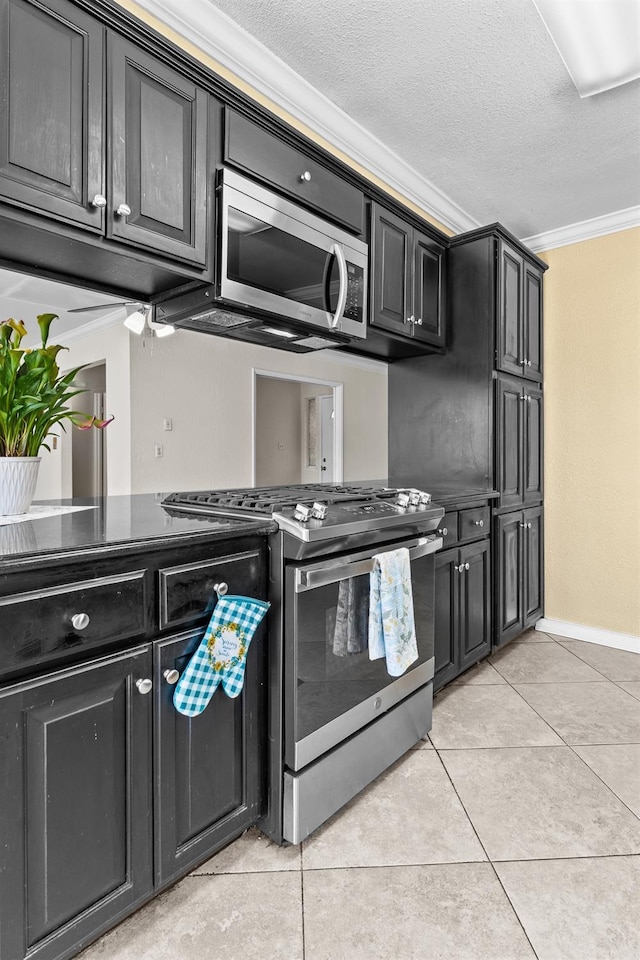 kitchen with stainless steel appliances, baseboards, ornamental molding, dark cabinets, and light tile patterned floors