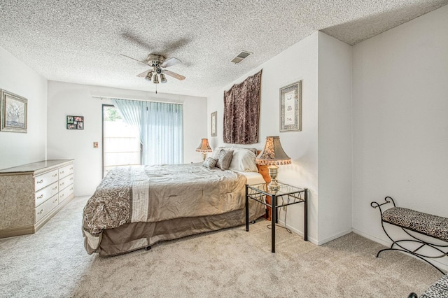 carpeted bedroom featuring a ceiling fan, a textured ceiling, and visible vents