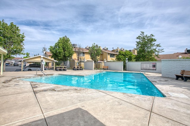 community pool featuring fence, a residential view, and a patio