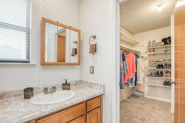 bathroom with vanity, a spacious closet, and a textured ceiling