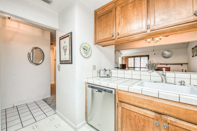 kitchen with tile countertops, stainless steel dishwasher, a sink, baseboards, and brown cabinetry