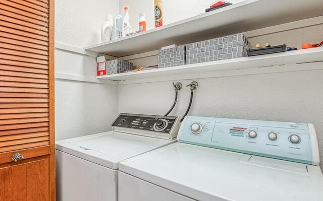 laundry area with separate washer and dryer, a textured wall, and laundry area