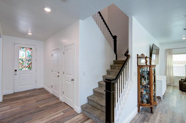 entryway with recessed lighting, wood finished floors, baseboards, and stairway