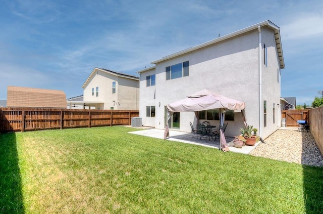 back of house featuring a fenced backyard, a yard, central AC, stucco siding, and a patio