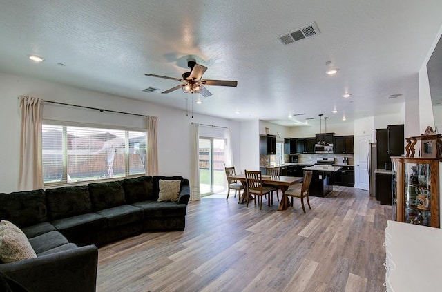 living room with ceiling fan, light wood-style floors, visible vents, and recessed lighting