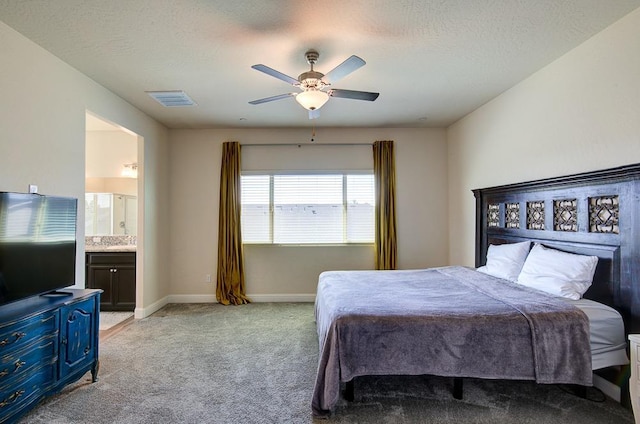 bedroom featuring light carpet, baseboards, visible vents, ceiling fan, and ensuite bath