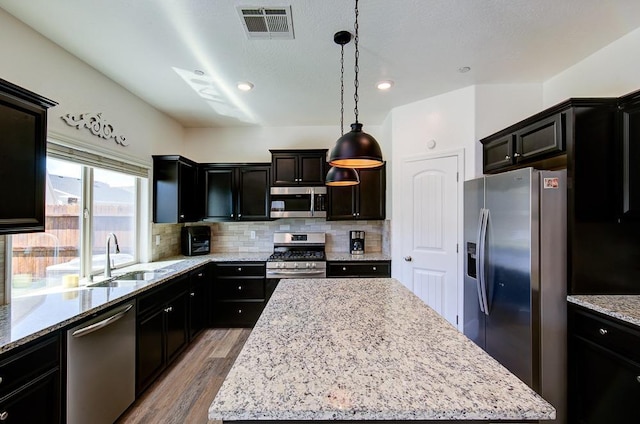 kitchen featuring light wood finished floors, visible vents, a sink, a kitchen island, and appliances with stainless steel finishes