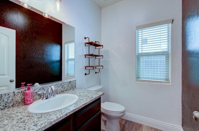 bathroom featuring plenty of natural light, wood finished floors, vanity, and toilet