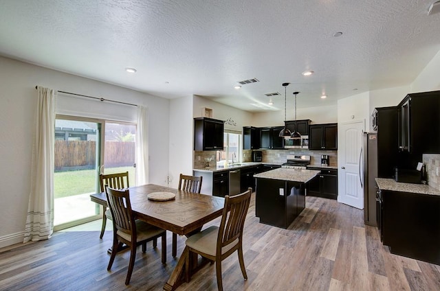 dining space with recessed lighting, wood finished floors, visible vents, and a textured ceiling
