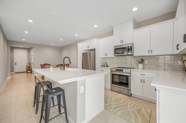 4103 Ash Rd, Madera, CA 93636 - kitchen with stainless steel appliances, a sink, light tile patterned flooring, tasteful backsplash, and a breakfast bar