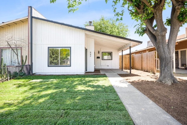 view of front of home with a front yard, a chimney, and fence